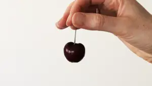 A hand holding a cherry.
