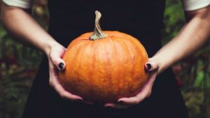 Someone holding a regular-sized pumpkin